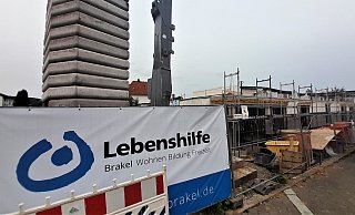 Am Bauzaun ist das Logo der Lebenshilfe zu sehen. Links hinter dem Neubau liegt die Wohnstätte direkt auf dem Nachbargrundstück. - Simone Flörke