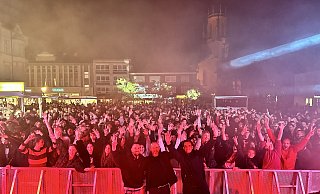 Das Organisationsteam (v. l.): Veranstaltungsverantwortlicher Tim Burrows, Henning Matthes, erster Beigeordneter der Stadt Gütersloh, und Michael Deppe, stellv. Leiter des Fachbereichs Kultur, vor der feiernden Menge. - Danielle Dörsing