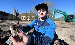 Grabungshelfer Dominik Schröder mit einem menschlichen Schenkelhalsknochen. Auf dem Gelände haben Experten mehrere Gräber entdeckt. - Thomas Kube