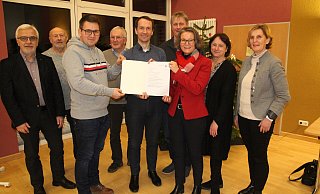Daniel Oepping und Michael Kasche nehmen den Förderbescheid aus den Händen von Ministerin Ina Scharrenbach entgegen. Alfred Krause, Karl-Heinz Kröger, Reinhard Scherer, Elmar Vielstich, Bianca Winkelmann und Susanne Sassenberg freuen sich mit. - Klaus Frensing