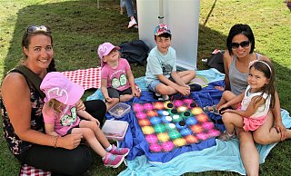 Auch Jennifer Pieper (l.), Hang Leonie Trautmann (r.) und ihre Kinder zog es zum Spielen (hier eine Variante von "Vier gewinnt") in den Schatten. - Meiko Haselhorst