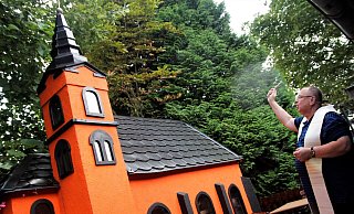 Pfarrer Wolfgang Sudkamp segnet die Kirche beim "Metzger mit dem Zopf" - und mit ihr gleich die ganze Gaststätte. Selbst das Objektiv des Fotografen bekam einen Tropfen Weihwasser ab, wie an dem hellen Fleck im Bild zu erkennen ist. - Meiko Haselhorst