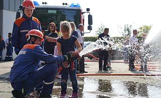 Die Helfer von der Jugendfeuerwehr zeigen den Jüngsten wie sie den Schlauch festhalten. Hier probiert sich Clara aus. - Yvonne Gottschlich