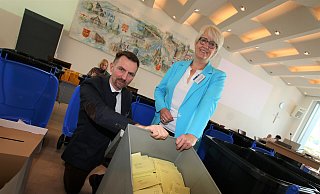 Im großen Sitzungssaal des Kreishauses Paderborn zeigen Christopher Schüngel, Leiter des Kreistagsbüros, und Annette Mühlenhoff, Vorsitzende des Wahlvorstands, eine Urne mit Unterlagen zur Weiterverarbeitung. Hierbei handelt es sich um Stimmen aus Bad Wünnenberg. - Rajkumar Mukherjee