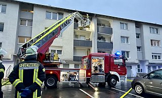 Bürener Feuerwehrleute kontrollieren von der Drehleiter aus die Traufschalung des Wohnblocks und löschen vereinzelte Glutnester oberhalb des Balkons im 3. Obergeschoss ab. - Ralph Meyer