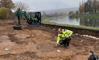 Ralf Mahytka, Archäologe bei der Landesgartenschau in Höxter, sichert die Spuren urzeitlicher Besiedlung am Weserufer, die bei den Bauarbeiten aufgetaucht waren. Bei den dunklen Verfärbungen handelt es sich um Pfostengruben und Lehmentnahmegruben. - LGS 2023 Höxter/Maike Koegel