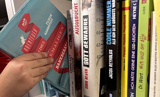 Der Roman "Die Abenteuer meines ehemaligen Bankberaters" von Tilmann Rammstedt wird aus einem heimischen Bücherregal gezogen. - Katharina Eisele