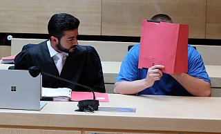 Der Angeklagte Ilya T. versteckt sein Gesicht hinter einem Aktendeckel. - Wolfgang Rudolf
