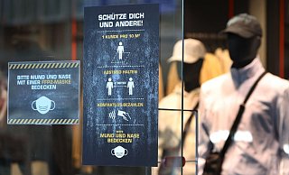 Ein Bekleidungsgeschäft in Augsburg weist auf verschiedene Corona-Regeln hin. - Foto: Karl-Josef Hildenbrand/dpa