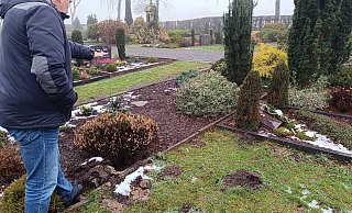 Wolfgang P. steht vor dem Loch auf dem Friedhof in Spradow, wo vorher das Bronzekreuz stand und deutet mit seiner Hand dessen ungefähre Höhe an. - Sven Hauhart