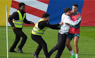 Ein Fan sprintet in Gütersloh auf den Trainingsplatz und umarmt Portugals Superstar Cristiano Ronaldo. - Hassan Ammar/AP/dpa