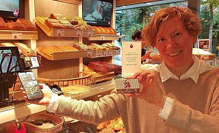 Friederike Tebbe, Geschäftsführerin der Konditorei und Bäckerei Welpinghus, präsentiert zwei der drei Möglichkeiten zum bargeldlosen Bezahlen: die geschäftseigene App und die Vorteilskarte. - Neue Westfälische