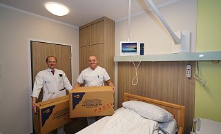 Chefarzt Florian Weißinger und Chef-Pfleger Robert Schwarz tragen symbolisch Umzugskartons in eines der neuen Zimmer der Onkologie. - Peter Unger