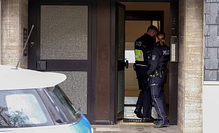 Polizisten stehen in Remscheid im Hauseingang eines Gebäudes, das im Zusammenhang mit einer Razzia gegen organisierte Kriminalität steht. - Sascha Thelen/dpa