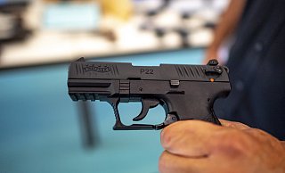 Ein Polizist zeigt eine Pistole der Marke Walther, Modell P22, die bei einer Hausdurchsuchung am Mittwoch sichergestellt wurde. - picture alliance