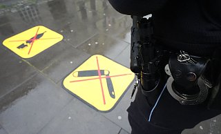 Eine Polizistin steht neben zwei Piktogrammen zum Glasflaschen- und Waffenverbot. - Marcus Brandt/dpa