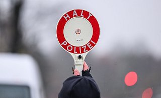 Ein Polizist hält während einer Verkehrskontrolle eine Polizeikelle in der Hand. (Symbolbild) - Robert Michael/dpa