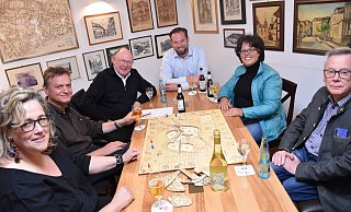 LGS-Logo-Designerin Barbara Fien (v. l.), Hans-Peter Rohler (TH OWL), Heinrich Sperling (LGS-Geschäftsführer), Heiko Böddeker (Gesellschaft für Wirtschaftsförderung im Kreis Höxter), Claudia Koch (LGS-Geschäftsführerin) und Michael Rindermann (Corveyer Weinhaus) spielen in den Bürgerstuben das Landesgartenschau-Spiel. - LGS
