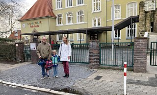 Schulpflegschaftsvorsitzender Andreas Bernard, seine Tochter Emma und Schulleiterin Silke Leuchter (v. l.) vor dem Schultor der Grundschule Falkstraße, vor dem sich früher "Elterntaxis" stauten. - Matthias Bungeroth