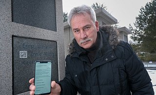 Detlef Wittig an der Urnenstele auf dem Altenhagener Friedhof. Hier soll sein Bruder Ernie die letzte Ruhe finden. Über einen QR-Code auf der Stele kommt man auf seine Wikipedia-Seite. - Foto: Andreas Zobe/NW