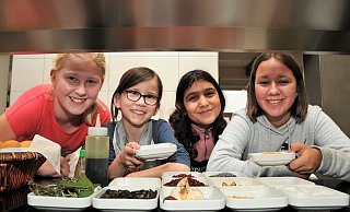 Lara, Svea, Evangelia und Giulia stehen hinter einem Tablett mit außergewöhnlichen Gewürzen und Streuzutaten, mit denen die Speisen dekoriert werden. - Waltraud Leskovsek