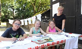 Finn (12), Yuna (9) und Enie (8) bemalen ihre T-Shirts. Mehrere Kinder haben ihre Arbeit schon beendet, ihre Hemden hängen dekorativ auf der Leine. Jana Spanke (r.) ist mit mit dem küstlerischen Einsatz rundumzufrieden. - Heidi Froreich