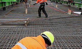 Bauarbeiter verbinden die Stahlmatten, die die Betonfahrbahn über die Werre stabilisieren sollen. Während der Brückenschlag gut voran geht, verzögert sich der Bau des Tunnels, der sich an die Brücke anschließen soll. - FOTO: PETER STEINERT