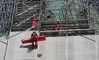 Ende 2018 simulieren die Höhenretter das Abseilen eines verletzten Arbeiters vom Gerüst, das damals noch den Turm einhüllt. - Marco Schreiber