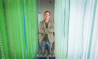 Futuristisch mutet der Bioreaktor mit seinem leuchtend grünen Inhalt an. Biologe Viktor Klassen hat an der Entwicklung der neuartigen Algenzucht-Anlage mitgearbeitet. Für die spätere Serienproduktion wird das Modell dann um ein Vielfaches vergrößert aufgebaut.   - Sarah Jonek