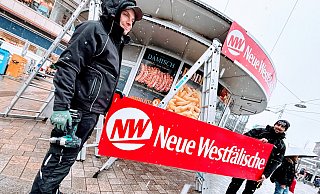 Fabius Notholt (l.) und Thomas Hornak von Declaro bringen die neue Werbung am Bratwurst-Rondell am Bielefelder Jahnplatz an. - Eike J. Horstmann