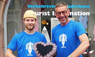 Tobias Schmidt (l.) und Karl Heinz Schäfer von der Tourist-Information Paderborn präsentieren die Libori-Artikel. - Stadt Paderborn