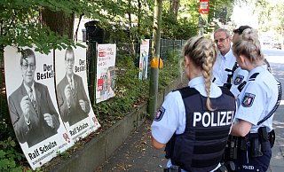 Dietmar Krämer von der BfB erklärt den Polizeibeamten, dass sie vor einem alten Wahlplakat ihres 2014 verstorbenen Parteikollegen Ralf Schulze stehen. - Jens Reichenbach