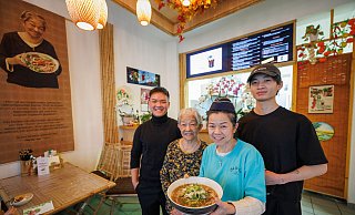Anh Duy Nguyen (v. l.), Namenspatronin und Rezept-Erfinderin Gái Nguyen, Chefin Thi Phuong Mai Nguyen und Gia-Bao Qiu mit einer dampfenden Schüssel Phô-Suppe. - Oliver Krato