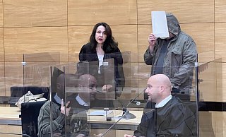 Nils T. hält sich erneut einenAktendeckel vor sein Gesicht, als er von Wachtmeistern neben seinerAnwältin Anne Patsch ins Gericht geführt wird. - Wolfgang Wotke