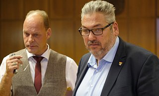 Freude sieht anders aus: Olaf Winkelmann (SPD, l.) und der amtierende Bürgermeister Achim Wilmsmeier schauen ein wenig fassungslos auf die Wahlergebnisse, die gerade auf der Leinwand im Ratssaal zu sehen sind.