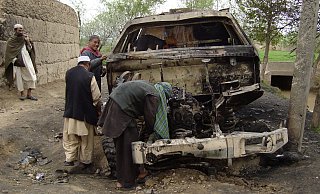 Afghanen untersuchen das Patrouillenfahrzeug, in dem drei deutsche Soldaten am Karfreitag 2010 starben. - picture alliance / ASSOCIATED PRESS
