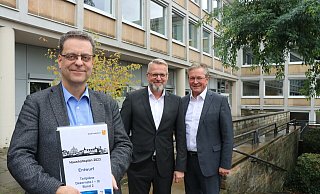 Beigeordneter und Kämmerer Markus Tempelmann hält einen Teil des Haushaltsplanentwurfs in den Händen. Er und Thomas Mönikes, Leiter des Amtes für Finanzen, sowie Bürgermeister Michael Dreier präsentieren die Kernaussagen des Zahlenwerks. - Mareike Gröneweg