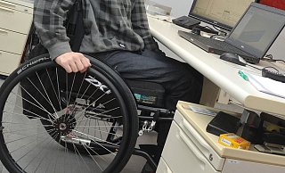 Ein Mann sitzt in einem Rollstuhl an seinem Arbeitsplatz am Schreibtisch. Inklusion ist ein w - dpa