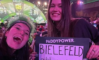 Mia (l.) und Ella Henrichsmeyer halten bei der Darts-WM im Ally Pally in London die Bielefelder Fahne hoch. - Henrichsmeyer