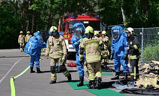 Vier Feuerwehrleute rüsten sich auf dem Parkplatz des Waldbades mit Chemieschutzanzügen aus. - Ralph Meyer