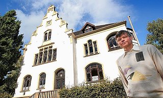 Ulrich Dittmar (großes Foto) vor seiner Musikschule. Das Innenleben der Uhr unter dem Dachgiebel nimmt einen gesamten Raum auf dem Dachboden ein. Zeitzeugen auf Bleiglas sind im kleinen Foto zu sehen. Wappen sowie die früheren Landgemeinden des Amts Ennigloh zieren die Scheiben im Konzertsaal. - FOTO: STEFFENS