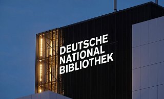 Der Schriftzug "Deutsche Nationalbibliothek" (DNB) leuchtet an einem 55 Meter hohen Gebäude der früheren Deutschen Bücherei. (Archivbild) - Sebastian Willnow/dpa