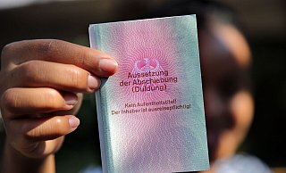 Eine junge Frau aus Afrika mit einem Ausweis für Flüchtlinge: «Aussetzung der Abschiebung (Duldung)». Darunter ist der Vermerk: «Kein Aufenthaltstitel!» - Wolfgang Kumm/dpa