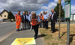 Landrat Jürgen Müller sprüht ein Piktogramm an der Spenger Straße in Enger in Beisein von Engers Bürgermeister Thomas Meyer (v. l.) und Fachbereichsleiter Gerd Althoff sowie Alexander Graf (Hiddenhausen), Wachleiter Dieter Lorenz sowie Spenges stellvertretendem Bürgermeister Bernd Pellmann. - Polizei/Katharina Uphoff
