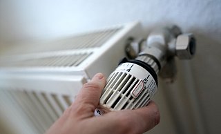 Eine Frau dreht an einem Heizungsthermostat. - Marcus Brandt/dpa