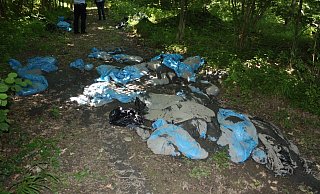 Die entsorgten Müllsäcke mit Schlamm im Wald. - Polizei