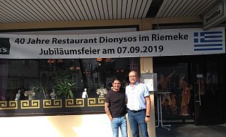 Gäste des Restaurants haben sich um Gerhard Hüllweg (r.) zusammen getan und überzeugten den Inhaber Konstantinos Karamihailidis (l.) von den Feierlichkeiten. - Moritz Jülich
