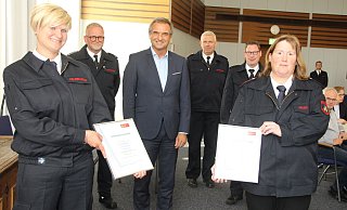 Die neuen Kinderfeuerwehrwartinnen Anne Hausmann (l.) und Michaela Schlichting mit dem stellvertretenden Wehrführer Andreas Außel (v. l.), Bürgermeister Burkhard Deppe, stellvertretenden Wehrführer Tobias Menne und Wehrführer Andreas Rehermann. - Burkhard Battran