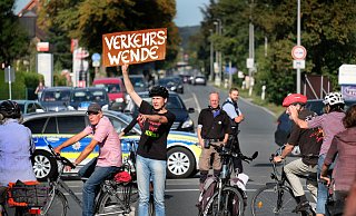 Ingold Klee steigt in Ummeln von seinem Fahrrad, holt ein Schild vom Gepäckträger und fordert alle 2.000 Protestanten zur "Verkehrswende" auf. - Andreas Frücht