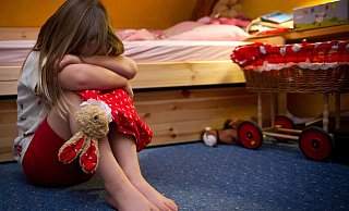 Ein kleines Mädchen sitzt weinend auf dem Fußboden in ihrem Zimmer. Viele Kinder benötigen ein Auslöser, um über die Taten zu sprechen. Die Kindersprechstunde soll das bieten. - Symbolfoto: picture alliance / dpa